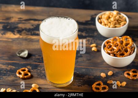 Kaltes, erfrischendes Oktoberfest-Bier mit Pretzels und Nüssen Stockfoto