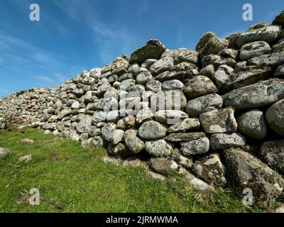 Alte, mit Flechten überzogene, trockene Steinwand aus runden Felsbrocken und Strandkieseln, Balnahard, Insel Colonsay, Schottland, Großbritannien Stockfoto