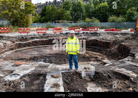 Meadowbank, Edinburgh, Schottland, Großbritannien, 25.. August 2022. Überreste des viktorianischen Eisenbahndepots St. Margaret's: Stadtarchäologen entdecken im Rahmen der Regeneration der Meadowbank einen viktorianischen Eisenbahnmaschinenschuppen und ein 20m-breites Drehscheibe (eines der frühesten Beispiele dieser Art). Der Standort wird für eine Wohnsiedlung entwickelt, aber die Überreste werden innerhalb der Wohnsiedlung erhalten bleiben. Im Bild: John Lawson, Ratsarchäologe. Kredit: Sally Anderson/Alamy Live Nachrichten Stockfoto