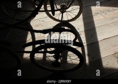 Schatten meiner alten Babykutsche auf meinem Holzboden auf dem Dachboden während des Sonnenuntergangs Stockfoto