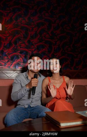 Fröhliches vietnamesisches Paar mit Datum in Karaoke Stockfoto