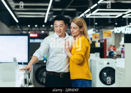 Glücklich vielfältige junge Familie Mann und Frau wählen elektronische Haushaltsgeräte, Shop für neue Wohnung im Supermarkt Stockfoto