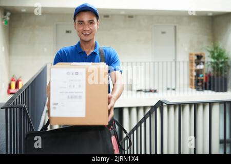 Glücklicher Postbote, der dir eine große Tasche gibt Stockfoto