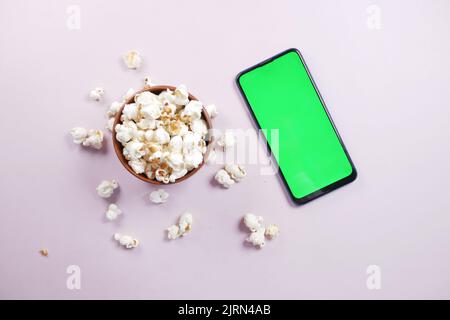 Draufsicht auf Smartphone und Popcorn auf dem Tisch Stockfoto