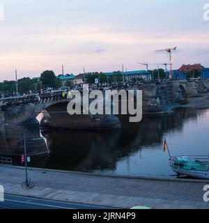 Dresden, Deutschland-August 17,2022: Bei Sonnenuntergang geht man auf einer Brücke über die Elbe Stockfoto