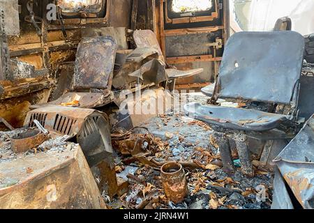 Verbrannte Sitze in verlassenen ausgebrannten Fahrzeugen, verkohltem Innenraum. Feuer beschädigt auf der Stadtstraße, Vandalismus oder Kämpfe während des Krieges. Nahaufnahme. Stockfoto