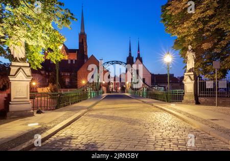 Grüne Eisenbrücke zur Insel Tumsky in der Nachtbeleuchtung am frühen Morgen. Breslau. Polen. Stockfoto