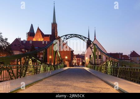 Grüne Eisenbrücke zur Insel Tumsky in der Nachtbeleuchtung am frühen Morgen. Breslau. Polen. Stockfoto