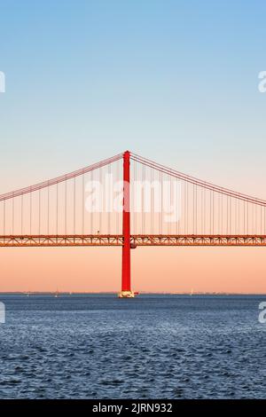 Ikonische orange-rote Hängebrücke über den Fluss Tejo in Lissabon, Portugal. 25 de Abril Bridge, 25.. April Bridge bei Sonnenuntergang in der goldenen Stunde. Speicherplatz kopieren. Stockfoto