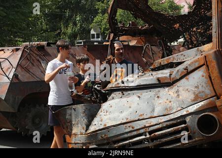 Non Exclusive: ODESA, UKRAINE - 25. AUGUST 2022 - Ein Mann und Jungen betrachten eines der russischen Militärfahrzeuge, die von den Streitkräften der Ukraine zerstört wurden Stockfoto