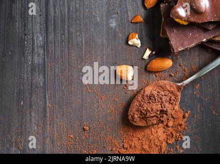 Kakaopulver und dunkle Schokoladenmandel auf schwarzem Holztisch Stockfoto