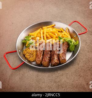 Gegrillte rumänische Fleischbrötchen, mititei oder mici, serviert mit Pommes Frites und dijon-Senf. Traditionelle rumänische Küche Stockfoto