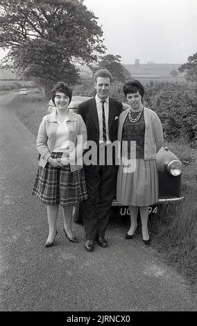 1950s, histroisch, in einer Landstraße, ein Mann und zwei Damen, die vor einem Wagen der Austin A30-Ära, England, Großbritannien, für ein Foto standen. Stockfoto