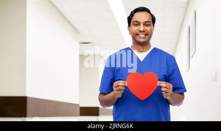 indischer männlicher Arzt mit rotem Herz auf Zwischenablage Stockfoto
