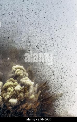 Fliegender Fels- und Staubsturm nach Sprengung der Detonatoren auf dem Bergbaugelände Stockfoto