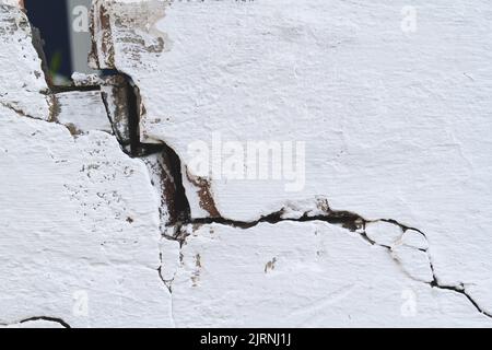 Steinwand mit tiefen Rissen. Bruch im Boden. Dürre und Folgen. Trockene Erde rissig. Nahaufnahme der Textur. Stockfoto