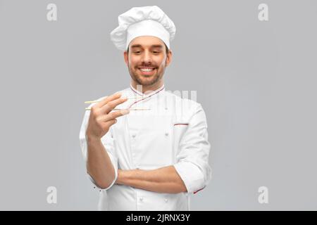 Fröhlich lächelnder männlicher Koch mit Essstäbchen Stockfoto
