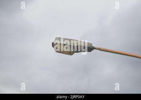 Moderne, schmutzige und hässliche Straßenlaterne gegen den Himmel grau Stockfoto