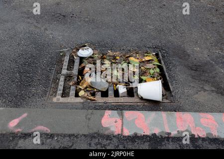 Müll blockiert Sturm Abfluss Rinne Graffiti Gehweg Stockfoto