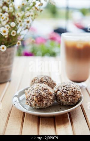 Gesunde vegane handgemachte Süßigkeiten - Gluten- und zuckerfreie natürliche Igel und Kaffee auf dem Holztisch. Gesundes Dessert. Stockfoto