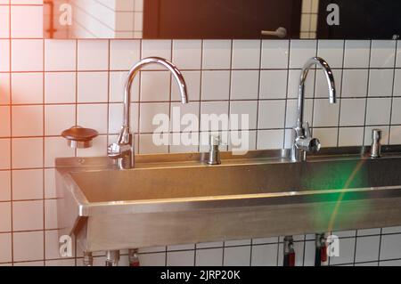 Handwaschbecken aus Edelstahl in einem modernen Gefängnis, Beleuchtung, Tönung. Stockfoto