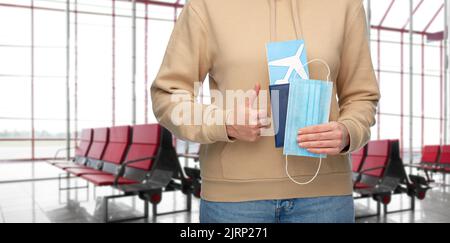Frau mit Maske, Reisepass und Ticket am Flughafen Stockfoto