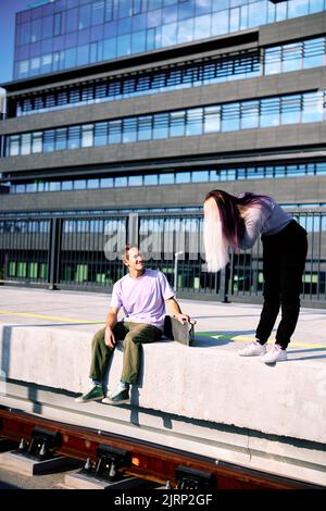 Ein glückliches Teenager-Paar sitzt am Bahnhof und macht Fotos. Stockfoto