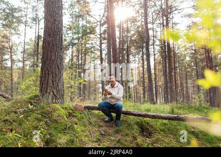 Mann mit Korb, der Pilze im Wald pflückt Stockfoto