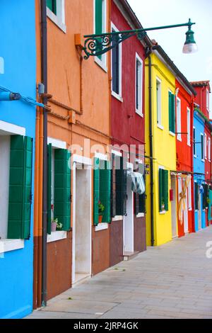 Nahaufnahme der Fassade von kleinen Häusern in verschiedenen hellen Farben. Im Hintergrund der klare blaue Himmel. Malerisches Straßenbild mit bunten Häusern. Typi Stockfoto