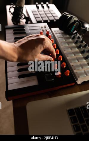 Die Hand des Mannes auf der Midi-Tastatur. Moderne technische Ausrüstung für ein Tonstudio, Musikstudio. Soundarbeit, Podcast, Arrangement. Musiker, Sänger, Stockfoto