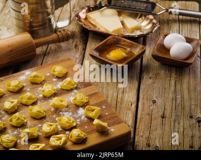 Rohe hausgemachte Ravioli auf einem Schneidebrett. Küchenutensilien, Zutaten auf einem hölzernen Küchentisch. Rezepte für hausgemachte Ravioli. Italienisches Essen. Da ist ar Stockfoto