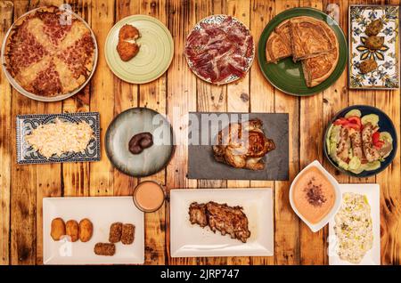 Set mit typisch spanischen Tapas, Alioli-Kartoffeln, Schinkenschale mit Eichelfütterung, Kroketten, galizische Empanada, Salmorejo mit Croutons, russischem Salat, ven Stockfoto