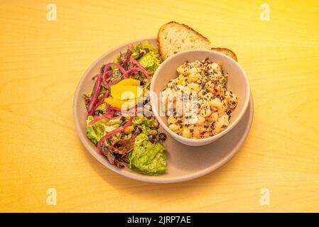 Ein veganer Menüteller mit einem Obstsalat und einer Schüssel weißer Bohnen mit einer Scheibe Brot Stockfoto