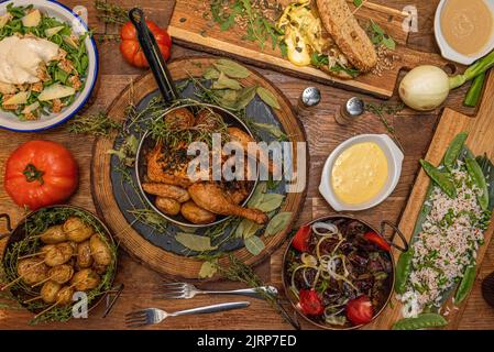 Superb Holzkohle gegrilltes Huhn von Gewürzen, zerknitterte Kartoffeln, Salate, Bauerntomaten mit Frühlingszwiebeln und Reis mit Erbsen umgeben Stockfoto