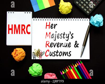 HMRC her majestys Einkommens- und Zollsymbol. Konzeptworte HMRC her majestys Einnahmen und Bräuche auf weißer Note auf schönem schwarzen Hintergrund. Unternehmen Stockfoto