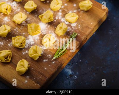 Appetitlich hausgemachte Ravioli auf einem Holzschneidebrett auf blauem Hintergrund. Nahaufnahme. Rezepte für die Hausmannskost. Kochbuch, Food Blog. Werbung, Stockfoto