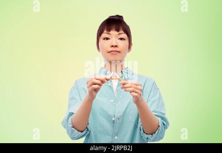 asiatische Frau bremst Zigarette über grün Stockfoto