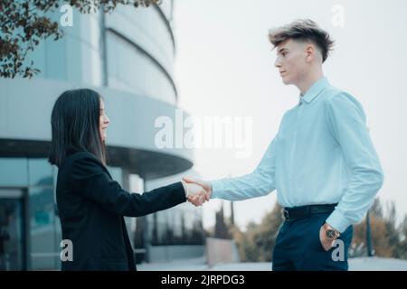 Ein Händedruck zwischen einem jungen Geschäftsmann und einer Geschäftsfrau Stockfoto