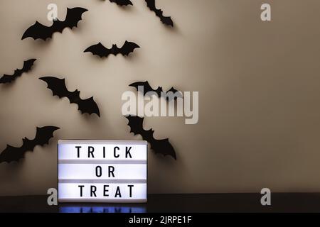 Leuchtkasten mit Text Trick or Treat und schwarzen Fledermaus Silhouetten, Halloween-Dekor Stockfoto