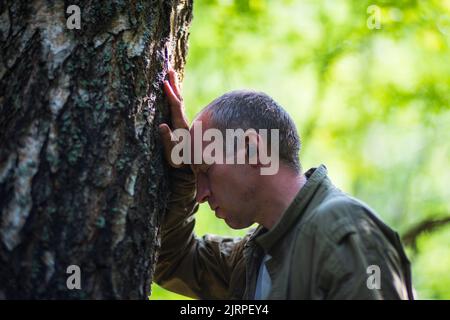 Ein Mann umarmt einen Baum im Wald. Rinde Holz.Pflege für die Umwelt. Die Ökologie das Konzept, die Welt zu retten und die Natur durch den Menschen zu lieben Stockfoto