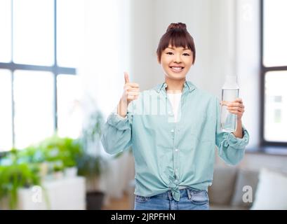 Glückliche asiatische Frau hält Glasflasche mit Wasser Stockfoto