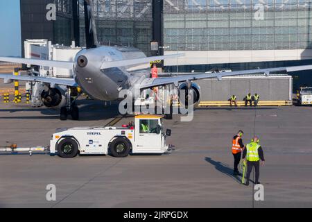 Mitarbeiter der Bodencrew mit Flughafenunterstützung, einem Fahrzeug mit Abschleppausrüstung und einem stationären geparkten Flugzeug/Flugzeug/Flugzeug/Flugzeug am LHR London Heathrow Airport. VEREINIGTES KÖNIGREICH. (131) Stockfoto