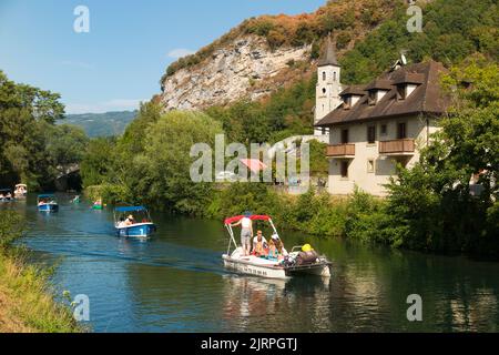 Gemietete / gemietete touristische Ausflugsboote fahren an einem schönen Haus in Chanaz am Kanal Canal de Savières im Südosten Frankreichs vorbei. August; Sommer-Hochsaison für den französischen Tourismus. (131) Stockfoto