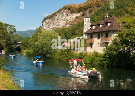 Gemietete / gemietete touristische Ausflugsboote fahren an einem schönen Haus in Chanaz am Kanal Canal de Savières im Südosten Frankreichs vorbei. August; Sommer-Hochsaison für den französischen Tourismus. (131) Stockfoto