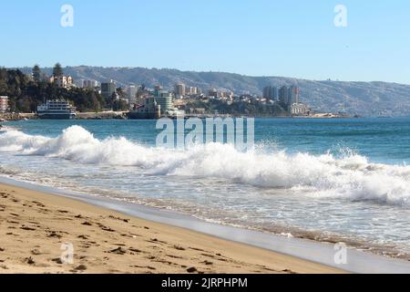 Wellen an einem Strand, mit Blick auf die Stadt Valparaiso, Chile, im Hintergrund Stockfoto