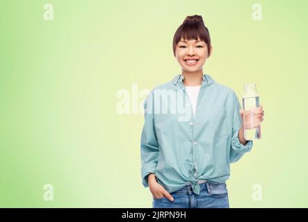 Glückliche asiatische Frau hält Glasflasche mit Wasser Stockfoto