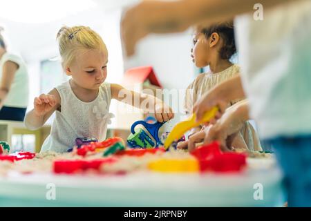 Kinder, die im Kinderzimmer mit kinetischem Sand spielen. Hochwertige Fotos Stockfoto