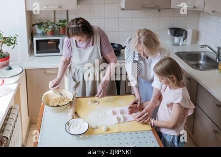 Drei Frauen in der Küche kochen gemeinsam Kuchen. Stockfoto