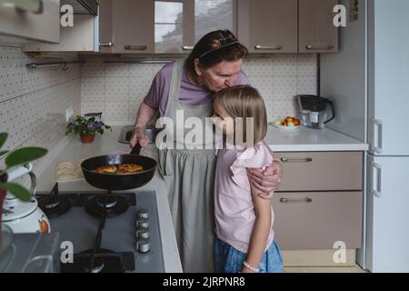 Eine ältere Frau in der Küche brät mit ihrer Enkelin Kuchen. Stockfoto