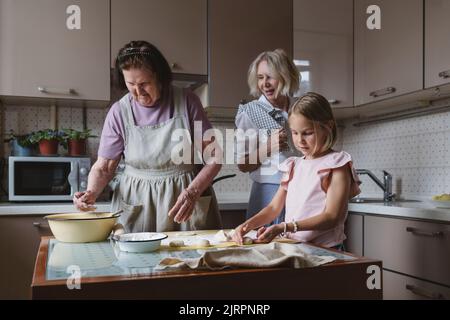Drei Generationen von Frauen kochen gemeinsam in der Küche. Stockfoto